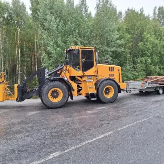 Gul hjullastare med släp på väg till ett markarbete