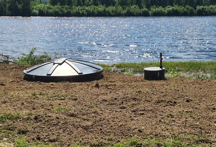 Nedgrävt minireningsverk med lock och pumpbrunn på en sjötomt i Västerbotten